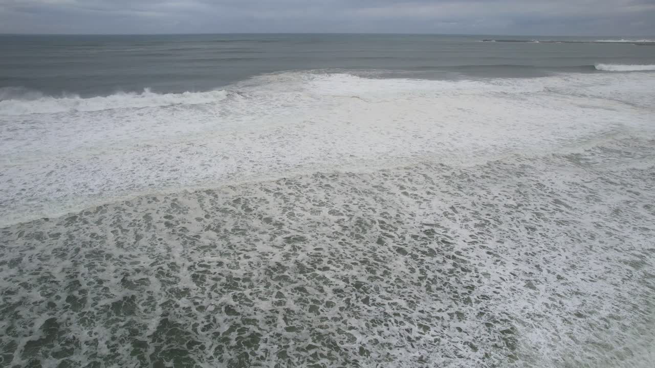 vista aérea del mar con fuertes olas que llegan a la playa de arena