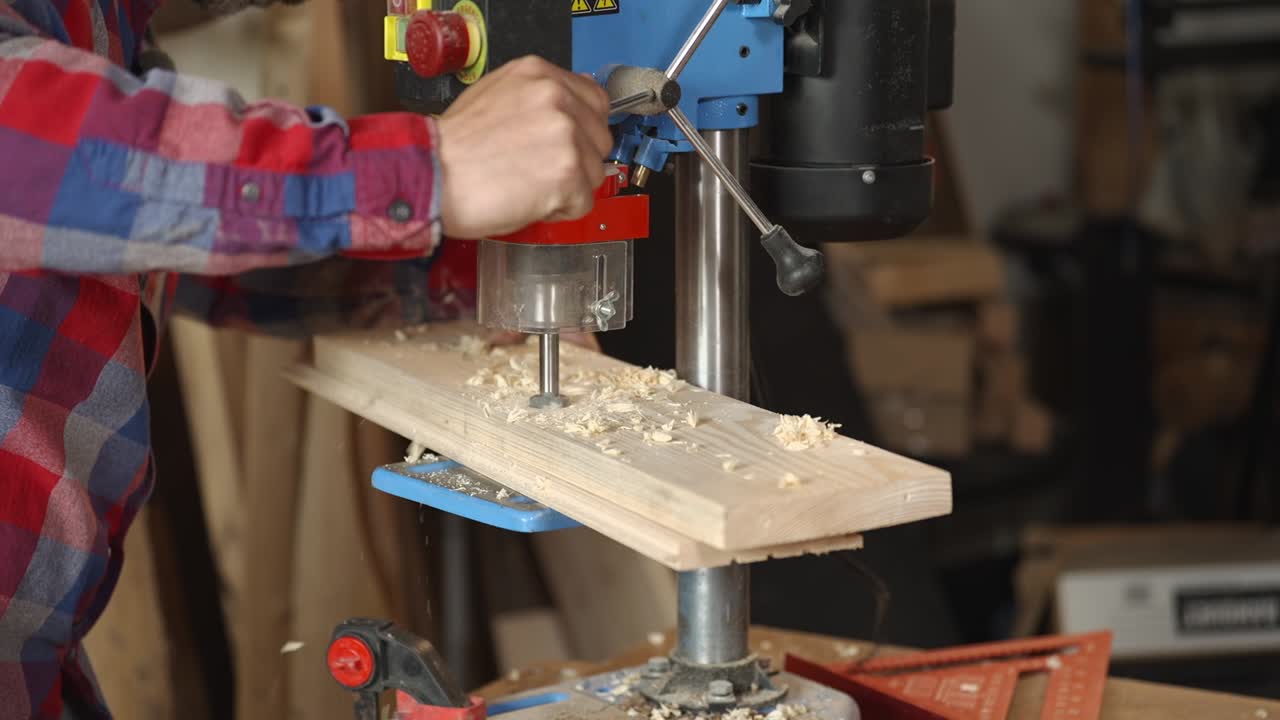 Primo piano di un falegname che fora il legno usando un trapano a colonna in officina. Processo di lavorazione del legno dettagliato con segatura e utensile di precisione, ideale per artigianato, fai da te e temi industriali