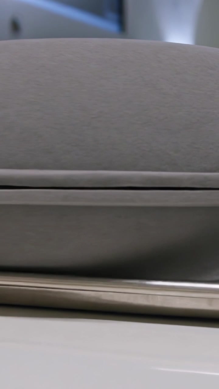 Vertical video: Zooming camera framing gray case on glossy desk revealing seam phone edge and vents