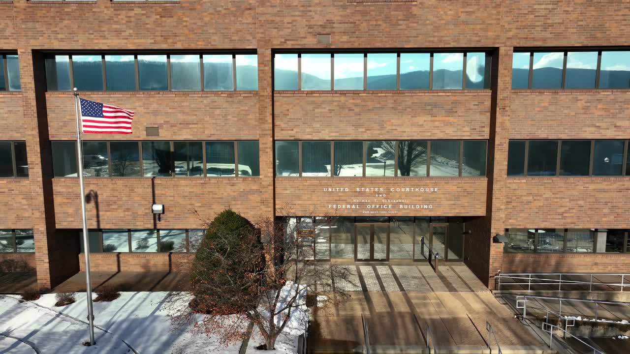 눈 덮인 날 우리 법원과 연방 건물 앞에서 흔들리는 미국 국기의 공중 상승 샷