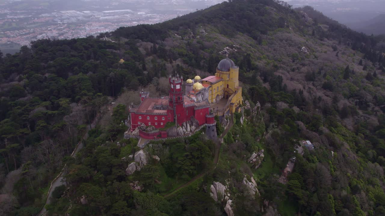 Wide shot of famous Pal&aacute;cio da Pena on hill top during day time, aerial