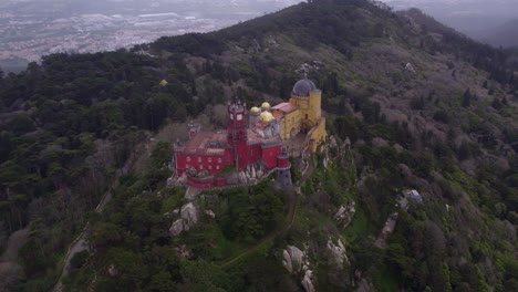 Wide-shot-of-famous-Palácio-da-Pena-on-hill-top-during-day-time,-aerial