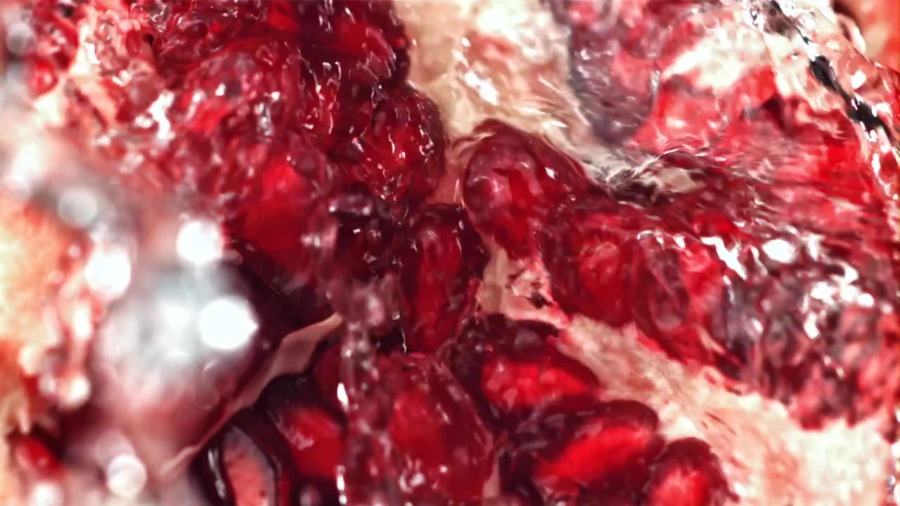 Primo piano di schizzi d'acqua su semi di melograno freschi
