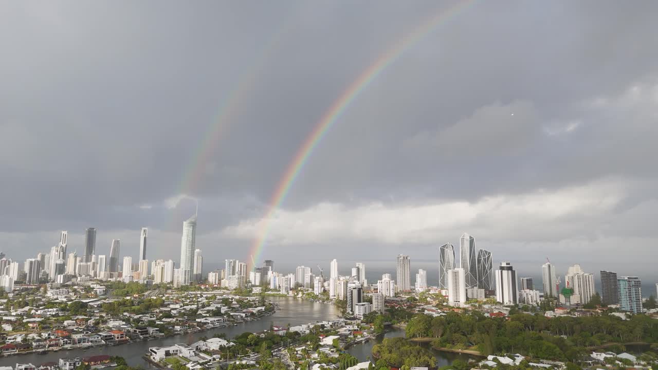 arcos de arco iris dobles sobre el horizonte de la ciudad y el océano