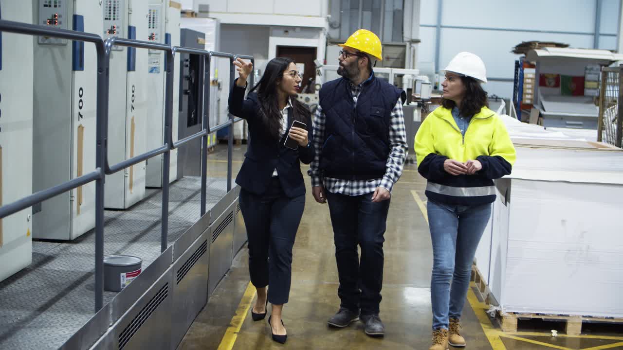 Front view of factory workers walking and talking at plant