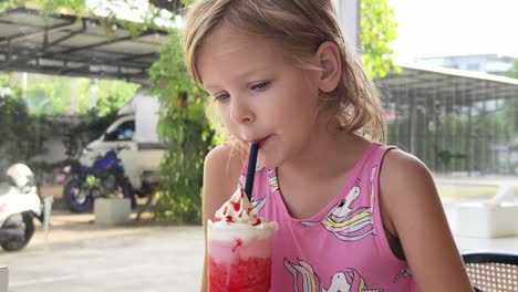 una chica bebiendo un batido de fresa.