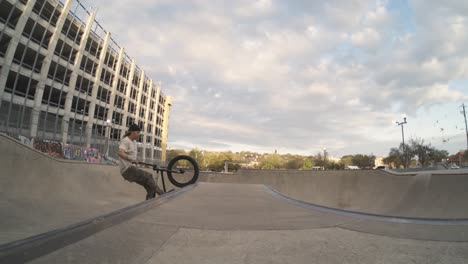 BMX-Fahrer-Macht-Einen-Riesigen-Tweed-Air-über-Der-Spine-Gap-Der-Skatepark-Bowl-In-Extremer-800-fps-Zeitlupe,-4K-Fisheye-Push-In-Bike-Trick-Bei-Sonnenaufgang