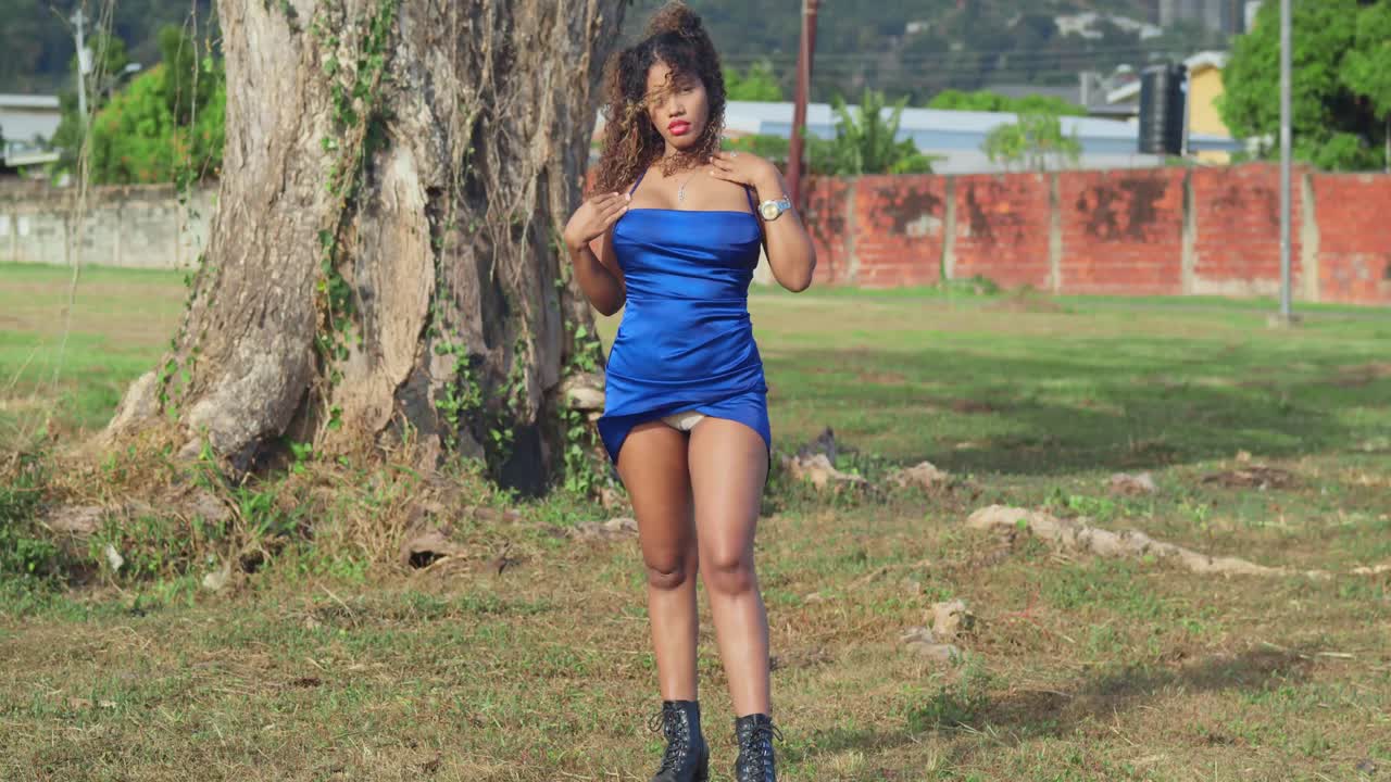una chica con cabello rizado en un vestido azul corto está disfrutando de un parque tropical en la isla de trinidad