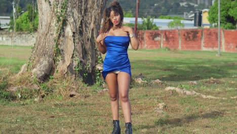 a girl with curly hair in a short blue dress is enjoying a tropical park on trinidad island