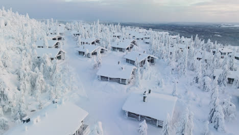 Vista-Aérea-Sobre-Una-Cabaña-Nevada-En-La-Cima-De-Una-Montaña-Caída,-Invierno-En-Laponia