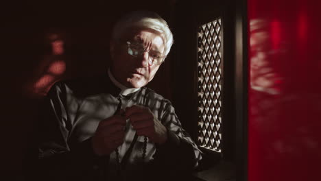 senior pastor sitting in confessional booth