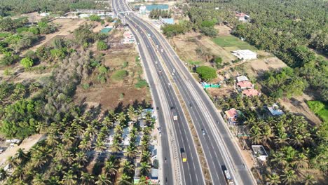 aerial: a modern maddur karnataka highway cuts through rural areas. features abundant palm groves, scattered houses, and a distant lake. perfect for infrastructure and regional development