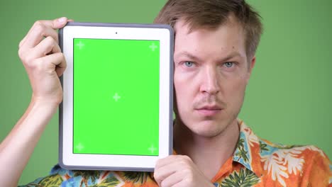 young handsome tourist man showing digital tablet
