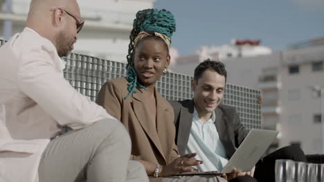 side view of diverse business partners looking at laptop screen