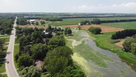 4k aerial drone footage of rural road winding around marsh pond and forest
