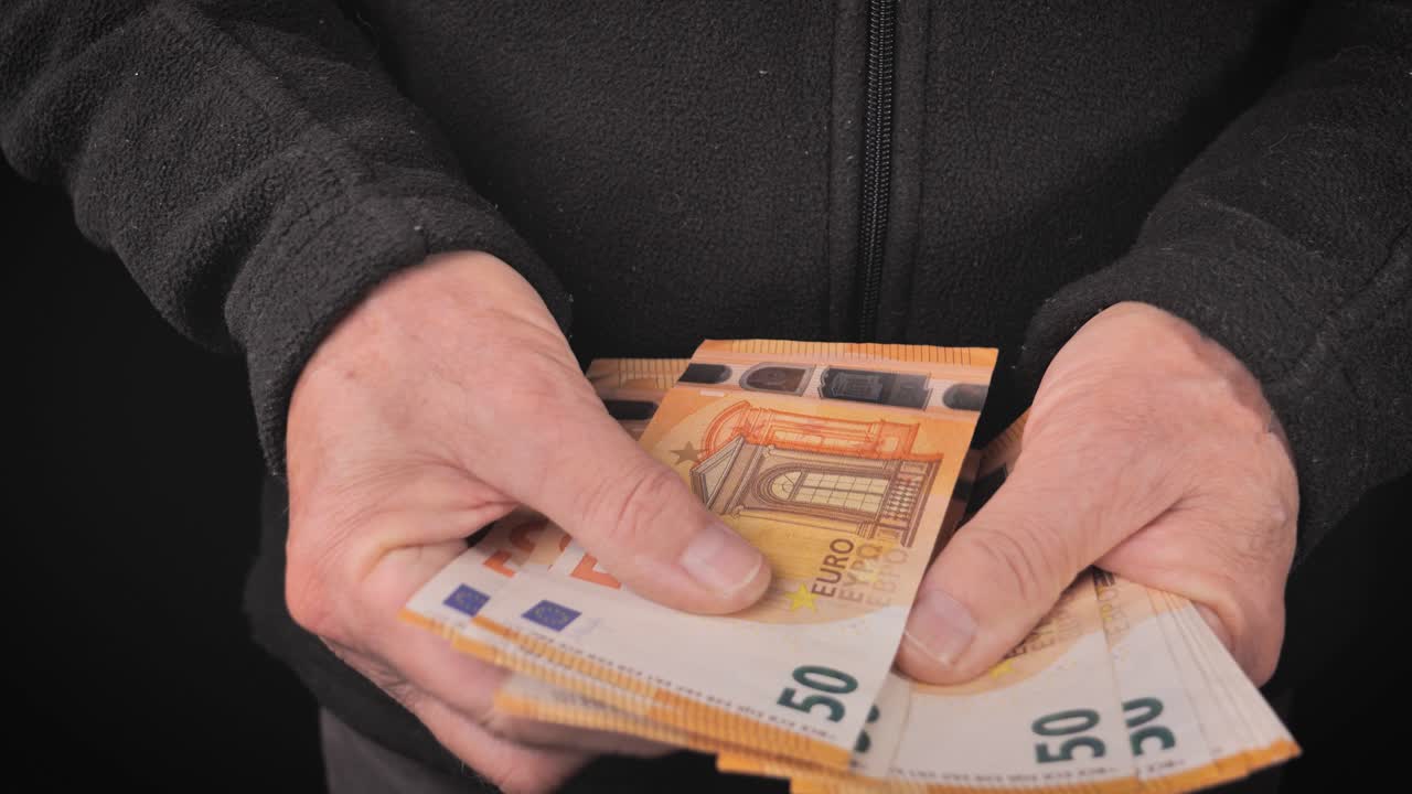 un hombre recibe y cuenta cincuenta billetes de euro con sus manos