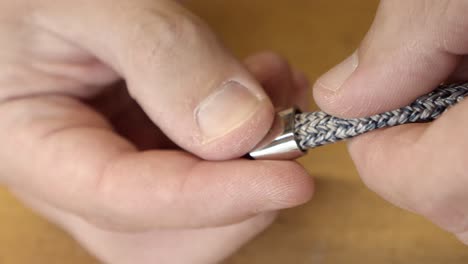 skillful craftsman putting on clasp on silver color bracelet, close up view