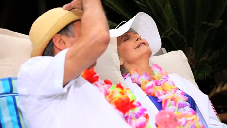 Mature-couple-with-garlands-sitting-and-smiling-in-sunshine