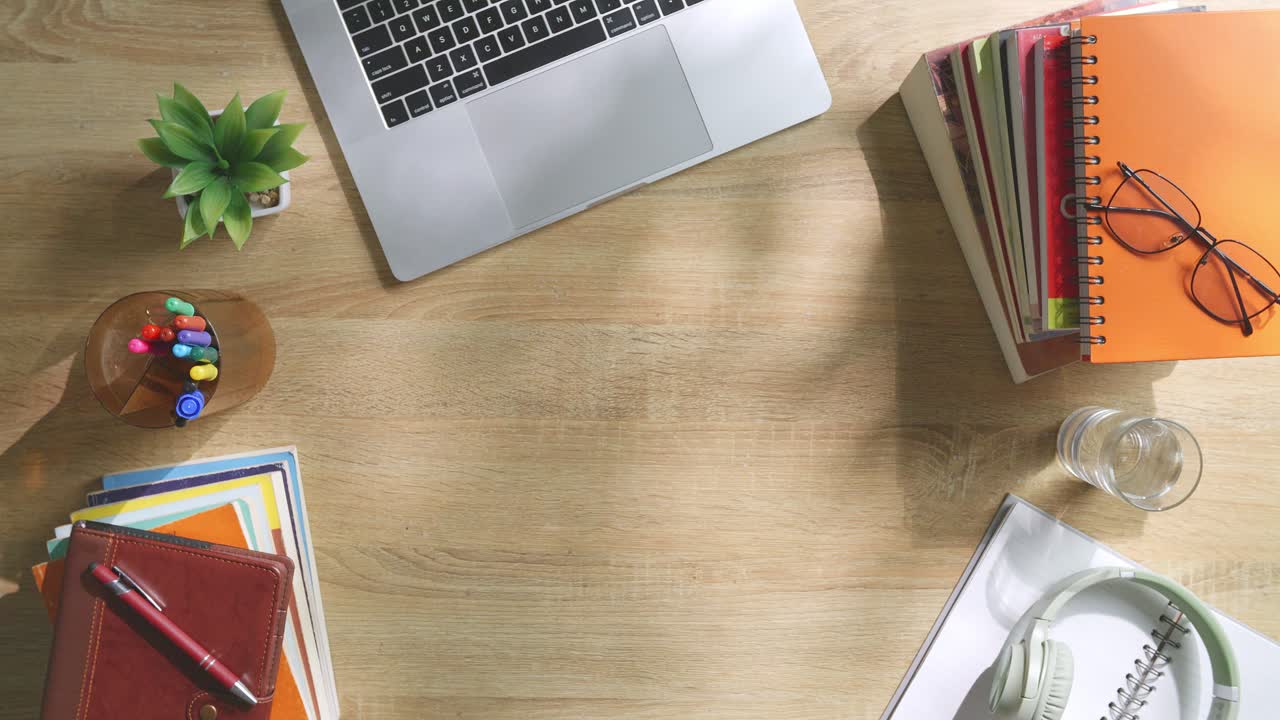 초록색 화면을 모방한 노트북 컴퓨터의 상단에서 아래로 볼 때, 펜, 안경, 그리고 물 한 잔을 가진 노트북 에 나무 사무실 책상 위에 크로마키 디스플레이가 있습니다.