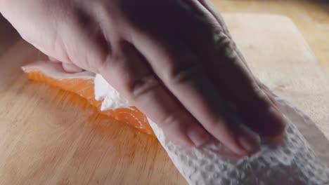 close shot of patting the fish skin dry on a salmon fillet prior to cooking in the kitchen