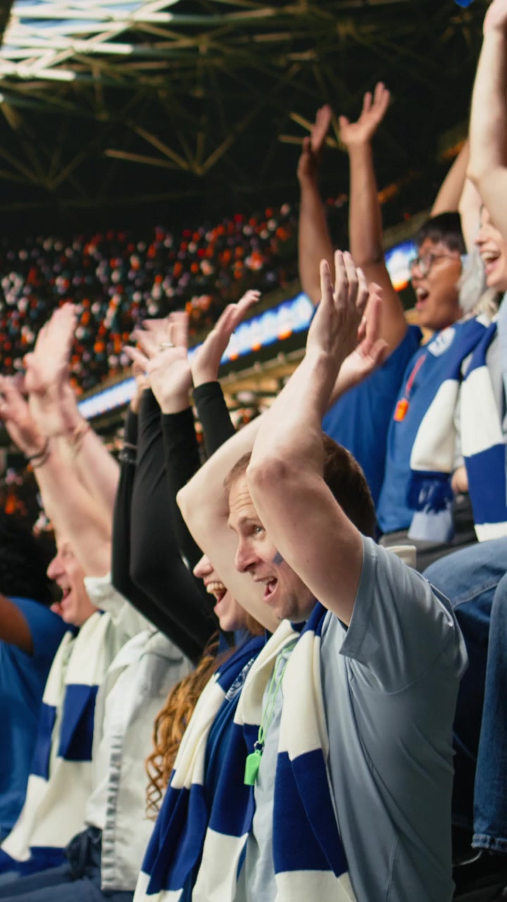 Video verticale: Tifosi di calcio della squadra blu che applaudono e alzano le braccia sugli spalti affollati.