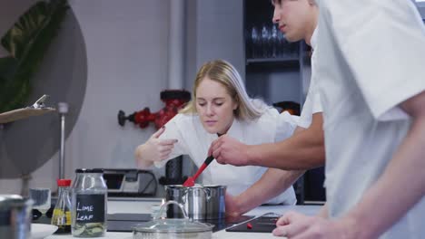 caucasian female chef wearing chefs whites in a restaurant kitchen preparing food