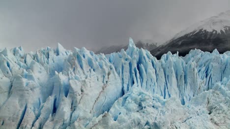 the spiked tops of a glacier stand against rugged mountains 1