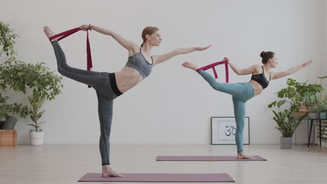 two young women using yogic belts during yoga class