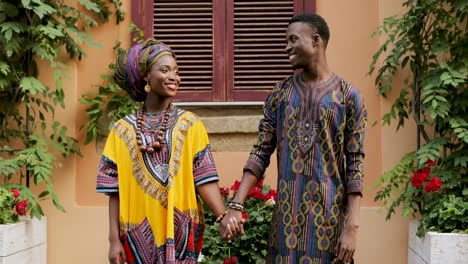 Portrait-Shot-Of-The-Young-Attractive-Man-And-Woman-In-Traditional-Clothes-Standing-Together-Hand-In-Hand-As-A-Couple,-Looking-At-Each-Other-With-Love-And-Then-Smiling-To-The-Camera