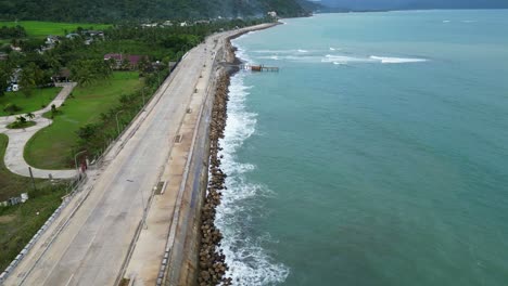 Impresionante-Toma-Aérea-De-Un-Dron-Desde-El-Pintoresco-Bulevar-Costero-Y-La-Carretera-Frente-A-Las-Olas-Del-Mar-Rompiendo-Contra-Los-Tetrápodos-De-La-Costa.