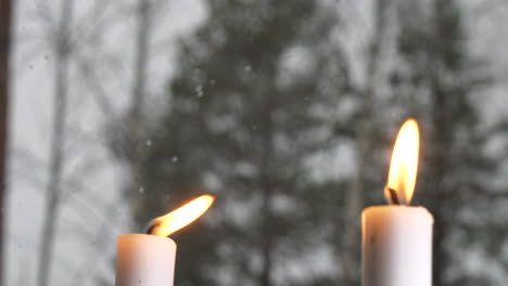 rack focus of winter snow falling to lit candles in window