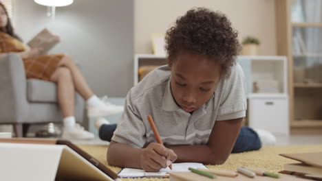 child doing homework on the floor