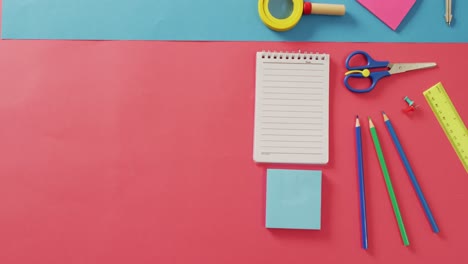 video of notebook with copy space and school items on pink and blue background