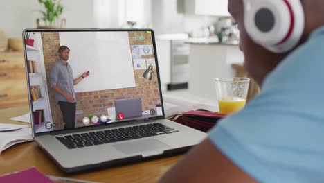 Adolescente-Afroamericano-Usando-Una-Computadora-Portátil-Para-Videollamadas,-Con-Un-Maestro-En-La-Pantalla