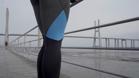 deportista concentrada estirando las piernas en un muelle de madera