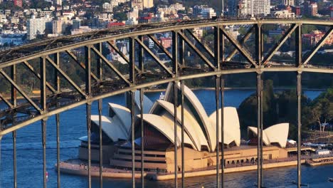 sydney opera house over harbour bridge, drone close up rising. beautiful sunset golden hour light.