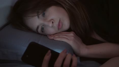 The-girl-works-on-the-computer,-lying-in-the-bed