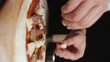 close-up portrait view on male chef hands seasoning pizza dough with cheese, moving camera