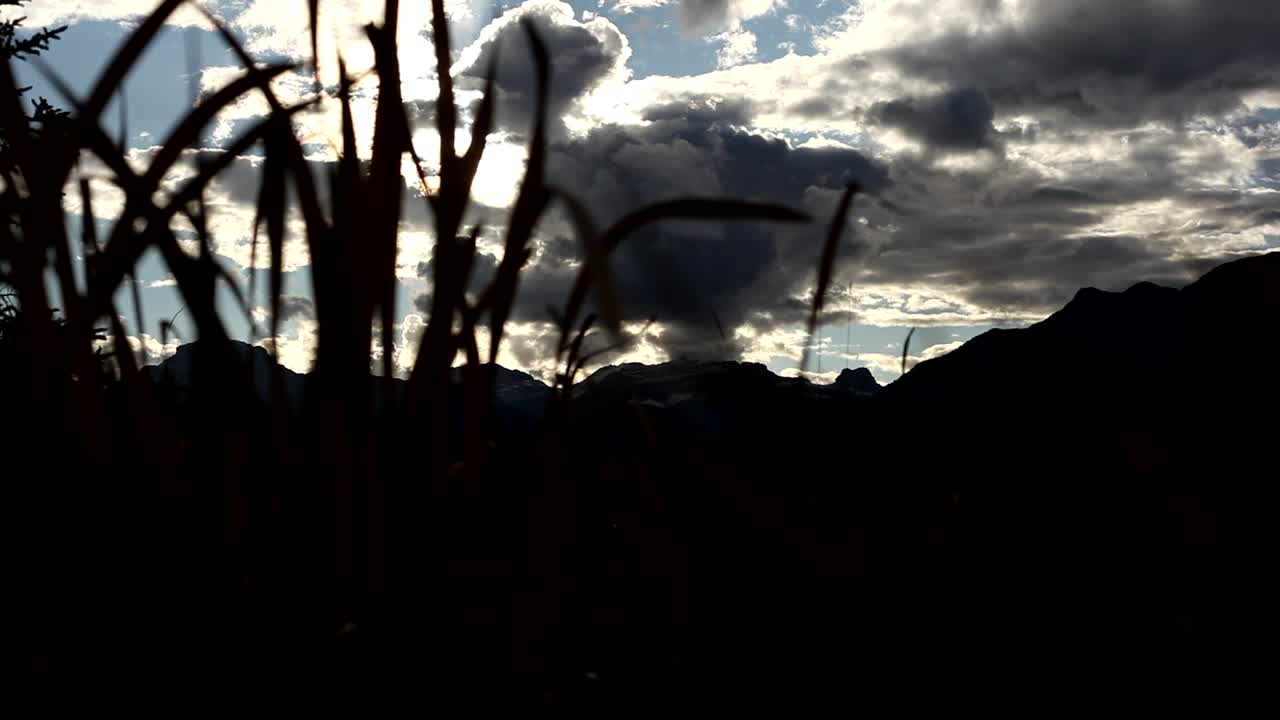 Mountain and clouds trough grass