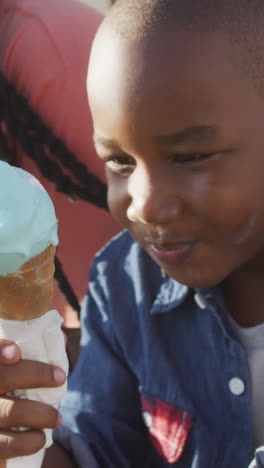 video of happy african american father and son eating ice creams on sunny day