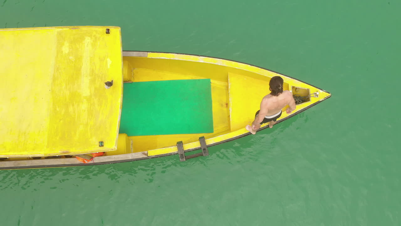 persona buceando en el agua desde un barco amarillo