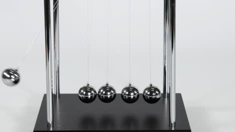 detailed view of a single ball impacting and transferring motion in a newton's cradle.