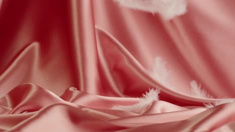 pink satin fabric with white feathers