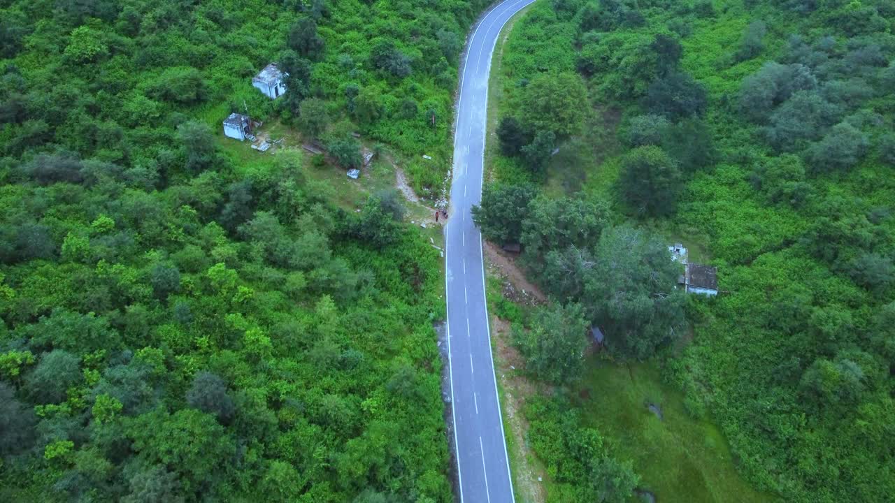 vista aérea de un avión no tripulado de una carretera a través de un bosque de selva verde exuberante con un telón de fondo montañoso durante el monzón en gwalior madhya pradesh india