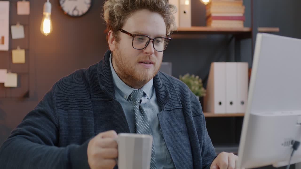 Man Drinking Coffee at His Desk