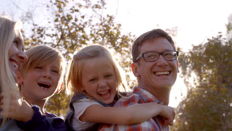 Young-white-family-having-fun-piggbacking-in-a-park