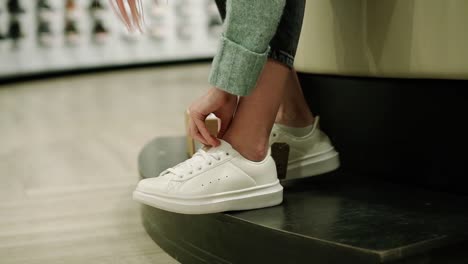 woman is trying new white sneakers in shoe store