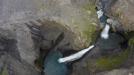 ascending top down shot of litlanesfoss waterfall on iceland between rocky mountains - rising top view