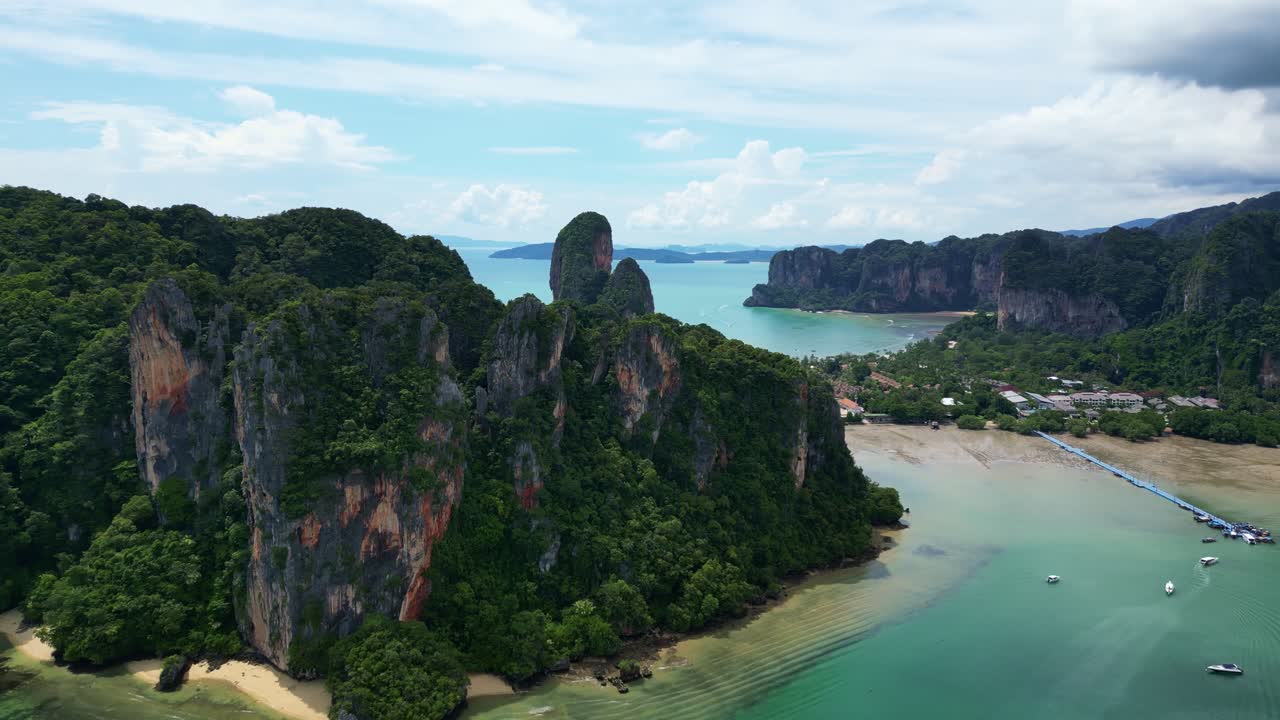 Aerial view of a coastal landscape featuring lush greenery, rocky formations, and tranquil turquoise waters.
