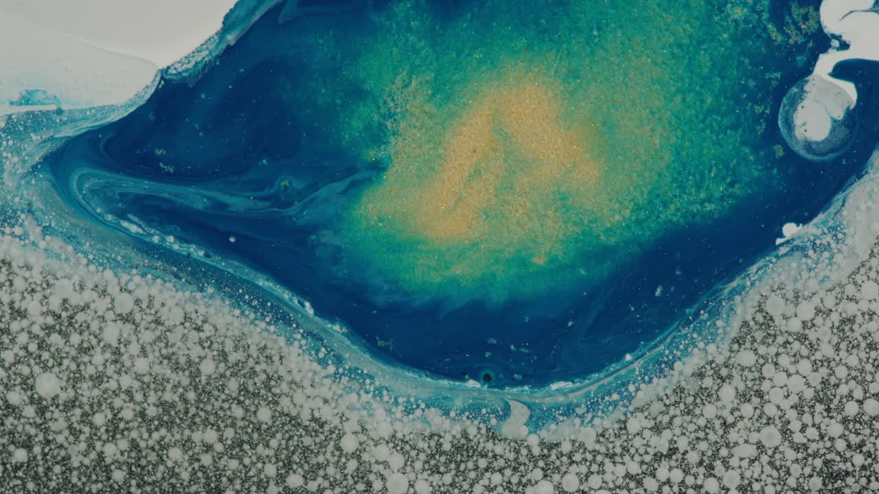 낮은 땅을 향해 거품이 이는 흰색 액체 잉크 근처에 흐르는 푸른 액체